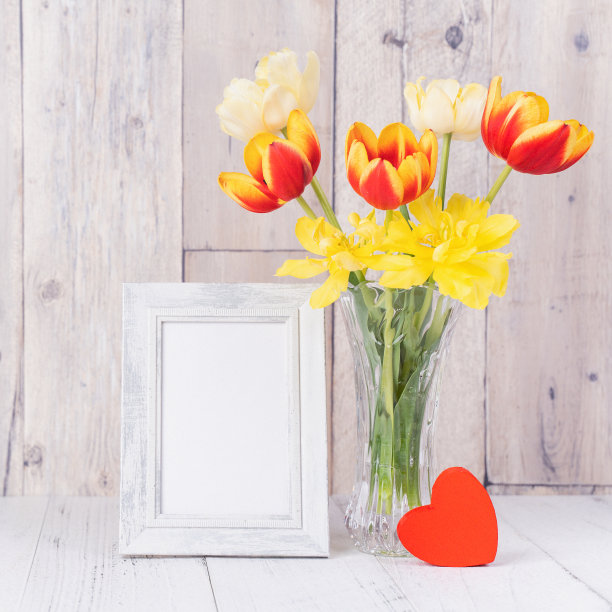 郁金香花在玻璃花瓶与画框装饰在木桌背景墙上在家，近，母亲节的设计理念。图片下载