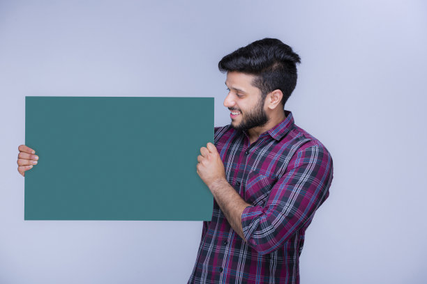 快乐的年轻人拿着一张绿色广告牌库存照片图片下载