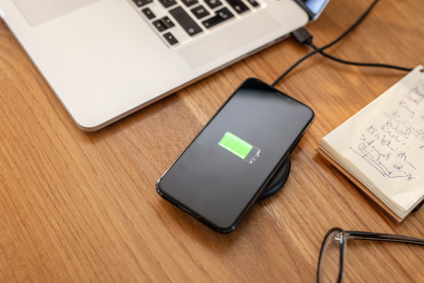 智能手机充电的无线充电器旁边的笔记本电脑图片下载