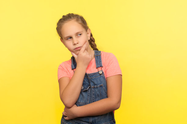 需要考虑!肖像聪明沉思的小女孩在牛仔工装裤抱着下巴和思考的解决方案图片下载
