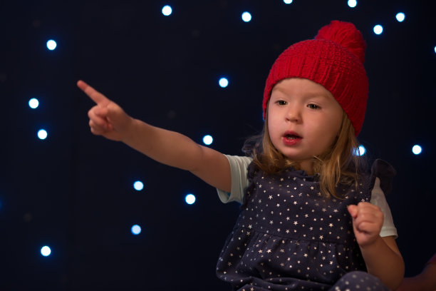 戴着红帽子的小女孩在星星面前微笑。图片下载