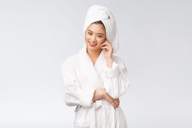 一个年轻快乐的亚洲女士在浴袍的肖像。孤立在白色背景。图片下载