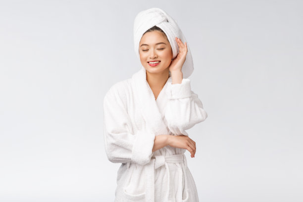 一个年轻快乐的亚洲女士在浴袍的肖像。孤立在白色背景。图片下载