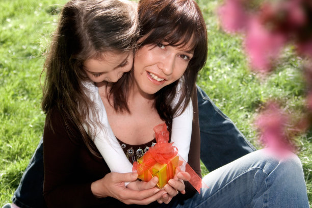 母女在绿草花园里拿着礼品盒图片下载