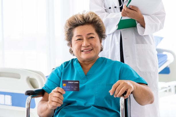 坐在轮椅上的亚洲老年妇女出示信用卡素材图片