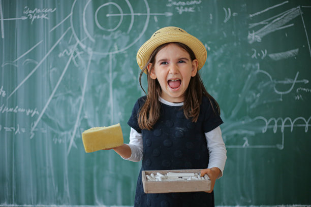 一个小学生在教室里微笑着拿着海绵图片下载