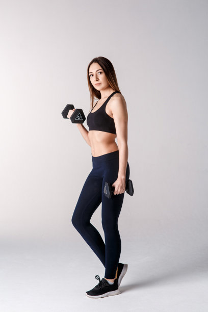 用哑铃锻炼的健壮女孩。有魅力的运动女孩在白色背景上的照片。力量和动力图片下载