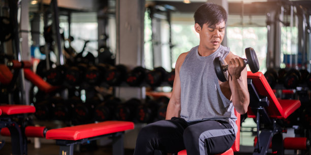 在健身房用哑铃锻炼的亚洲青年男子肖像图片下载