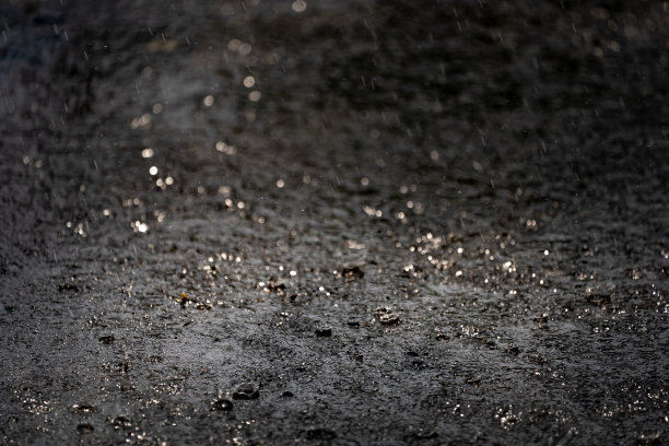 雨落在地面上，黑色的雨天气背景，水泡和水花在水面上，刷新自然上的水滴水模式，美丽的散水滴水图片下载