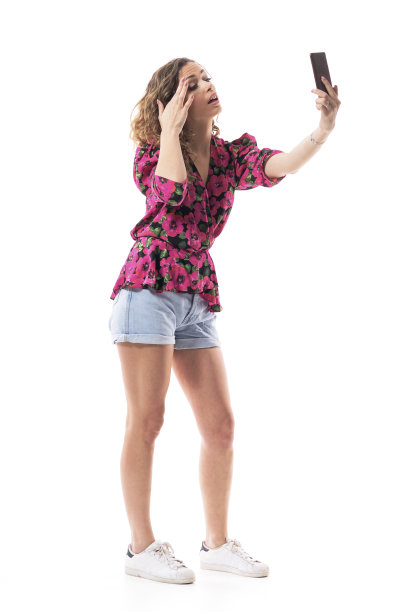 年轻时尚的女人用手机屏幕作为镜子调整眉毛妆容图片下载