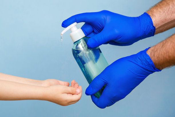 用带着手套的手把肥皂液倒进孩子的手上。安全远离疾病和病毒。图片下载