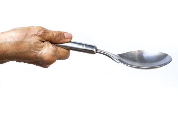 妇女右手握不锈钢勺，白色背景，特写，选择性聚焦，厨房用具概念图片下载