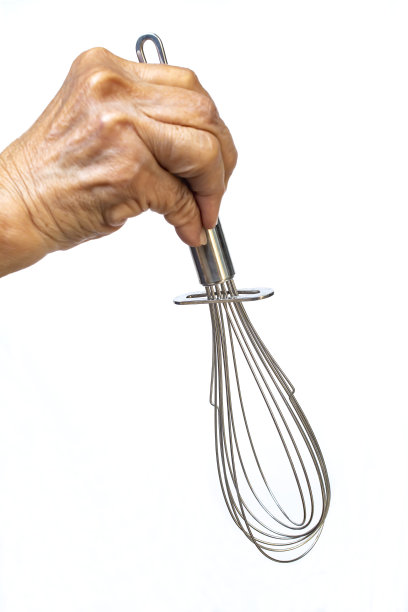 妇女的右手拿着不锈钢搅拌器烹饪在白色背景，近距离拍摄，选择性聚焦，厨房用具的概念图片下载