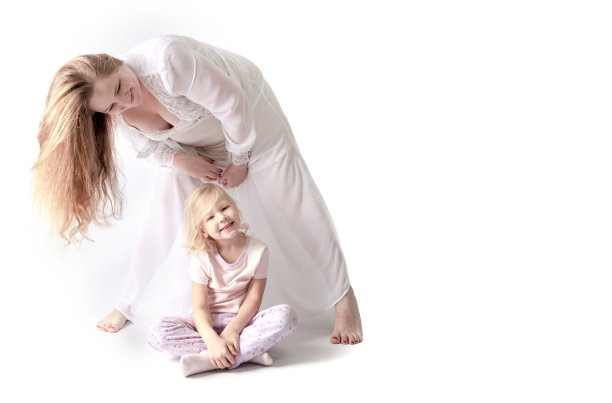 穿着睡衣的超重或怀孕的母亲和女儿玩得很开心。健康生活方式理念。明亮背景下的儿童和成人。幸福的家庭在一起。留白图片下载