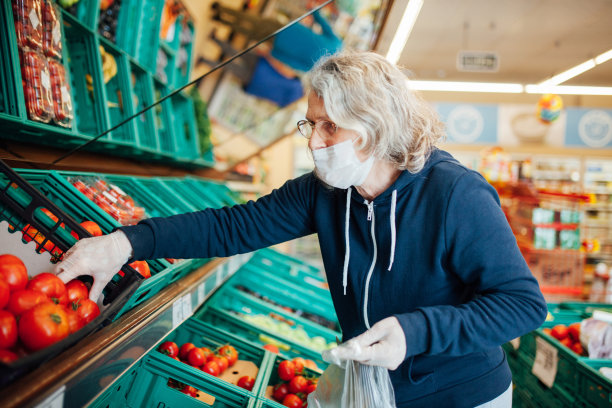 中年妇女戴着防护口罩在杂货店购物图片下载