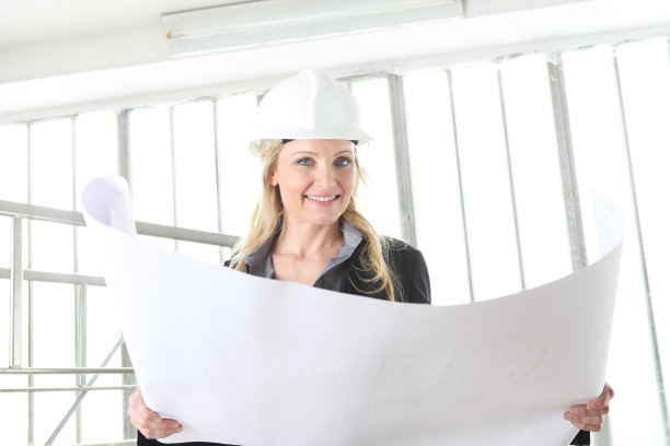 微笑的女建筑师或建筑工程师在建筑工地看图纸图片下载