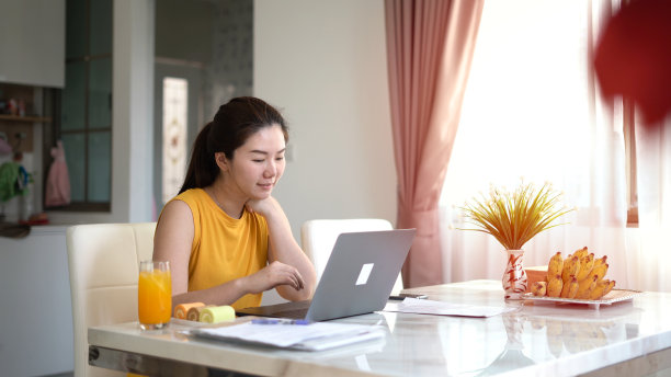 微笑的女人在家用笔记本电脑工作图片下载