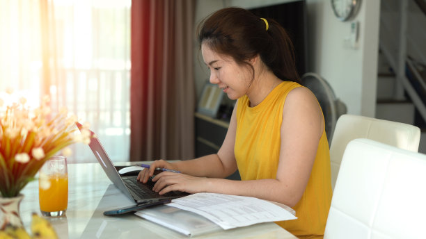 微笑的女人在家用笔记本电脑工作图片下载