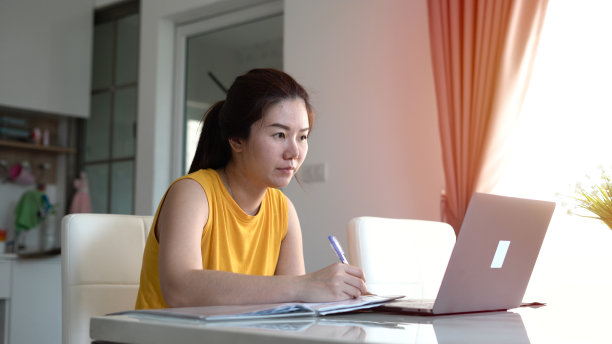 微笑的女人在家用笔记本电脑工作图片下载