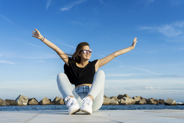 一个年轻美丽的女人与长头发坐在散步对蓝色的天空，而看着远离一个大大的微笑图片下载