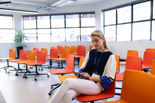 一个白人女人在会议室里玩她的平板电脑图片下载