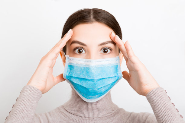 一名年轻女子戴着医用口罩的照片，背景为白色。保护你的健康。冠状病毒的概念图片下载