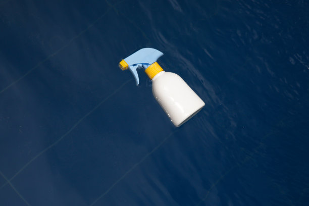 空白的白色防晒霜瓶子漂浮在游泳池的水图片下载