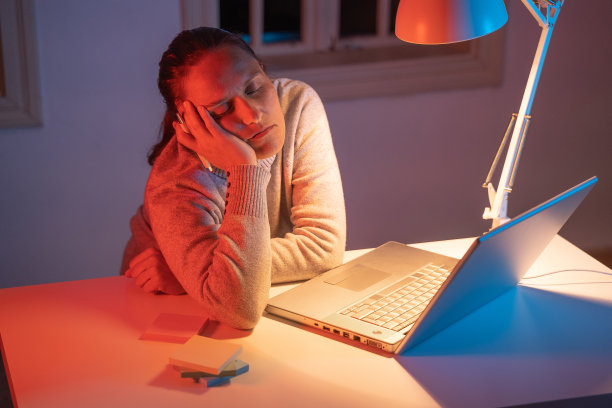 年轻的上班族在家里工作，深夜。COVID-19隔离。在她的桌子上睡觉。图片下载