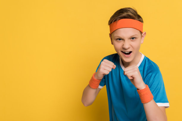 有攻击性的孩子在黄色背景下挥舞拳头并尖叫图片下载