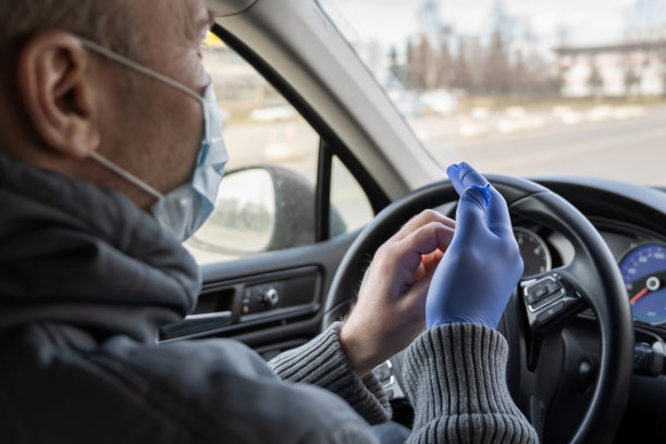 戴着医用口罩的男人戴上橡胶手套，在开车时保护自己免受细菌和病毒侵害。新冠病毒。大流行图片下载