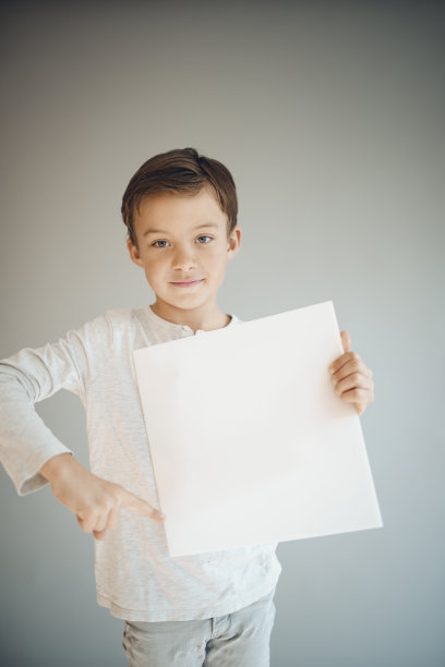 男孩在灰色背景前举着白色的牌子图片下载
