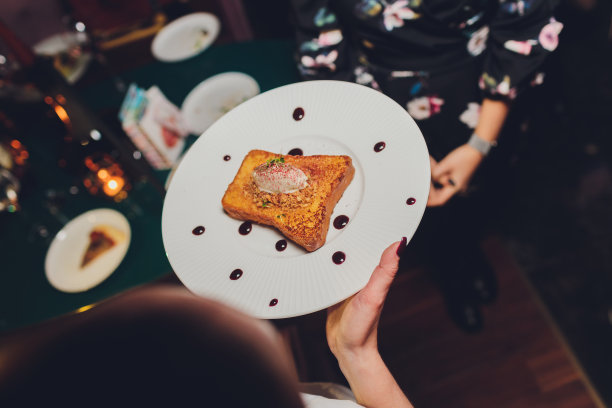 女服务员端着一盘白色芝士蛋糕的手，蛋糕像冰淇淋一样插在棍子上，上面有水果和覆盆子。意大利食物。图片下载
