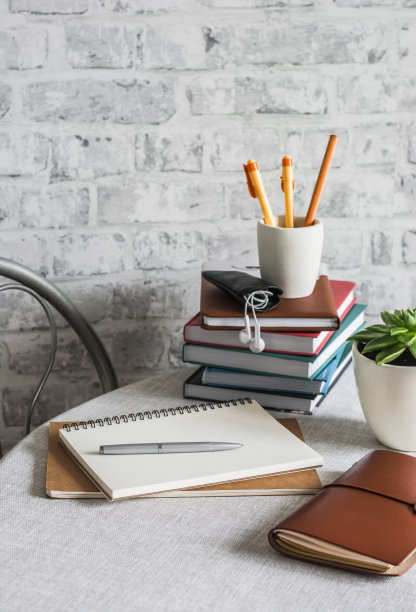 家庭在线学校教育。在一个明亮的房间里，桌子上堆放着书、笔记本、钢笔、铅笔、记事本、电话图片下载