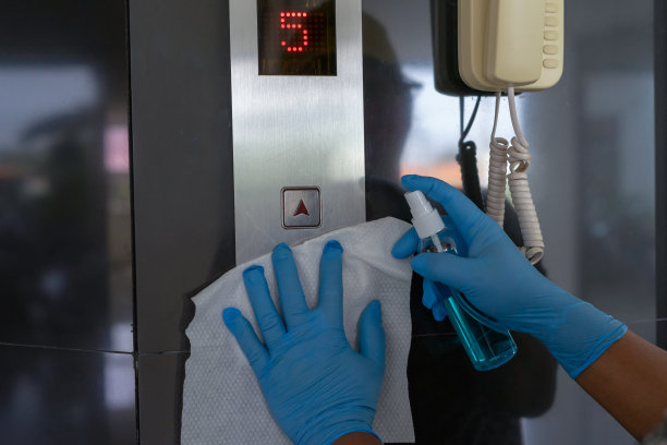用湿纸巾和酒精消毒液喷雾瓶擦拭电梯按钮控制面板。消毒、清洁和保健、抗冠状病毒(COVID-19)。有选择性的重点。图片下载