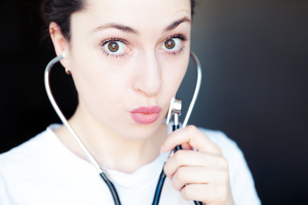 年轻女人拿着听诊器等医疗设备，深色背景，健康医疗保险、新冠病毒概念图片下载