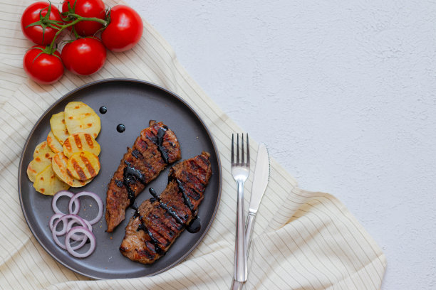 西红柿猪肉排。猪肉牛排在家庭食品概念上的灰色背景俯视图。餐厅的菜单设计。图片下载