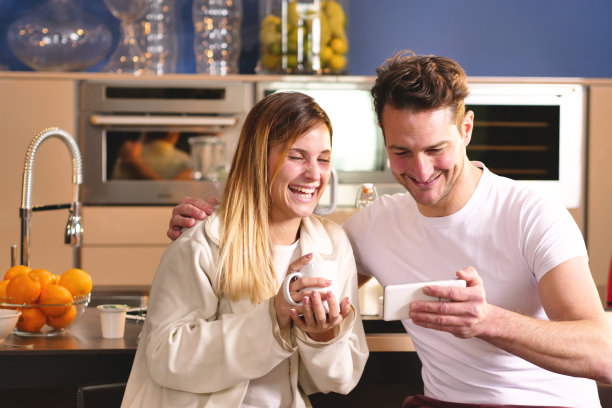 情侣在厨房里看手机上的假日照片图片下载