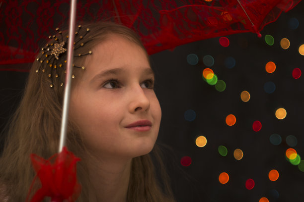 一位美丽的年轻姑娘饶有兴趣地把目光移开。黑色背景与散景。副本的空间。图片下载