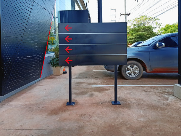 黑色的标志设置在水泥地面前的建筑物和灰色的汽车停在后面图片下载