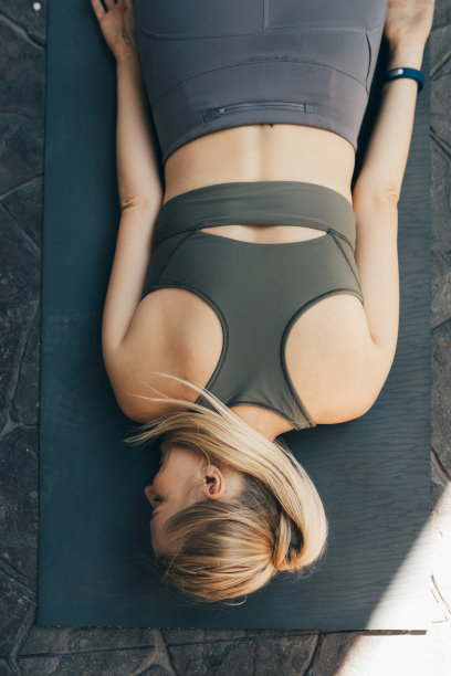 头顶上的一个健康的金发女人在运动服躺在一个运动垫子后锻炼图片下载