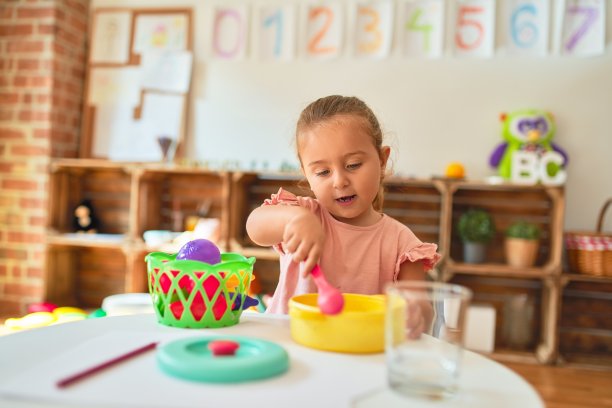 金发碧眼的蹒跚学步的小女孩在幼儿园用塑料食品玩饭图片下载