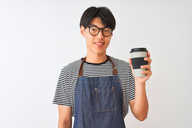 一名中国咖啡师，穿着围裙，戴着眼镜，在孤立的白色背景上端着咖啡，面带微笑，自信地笑着露出牙齿图片下载