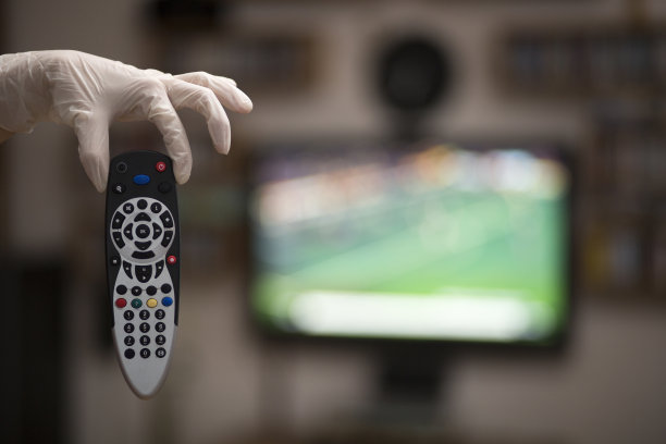 手持电视遥控器与医疗手套。待在家里和新冠肺炎概念。图片下载
