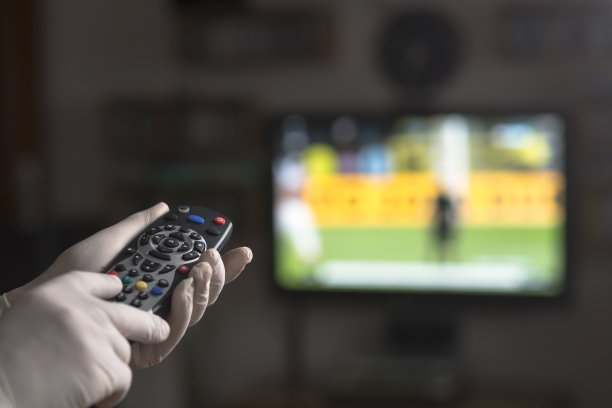 手持电视遥控器与医疗手套。待在家里和新冠肺炎概念。图片下载