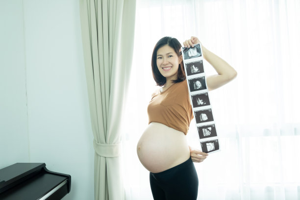 美丽的亚洲孕妇展示她的婴儿超声波扫描图，面带微笑图片下载