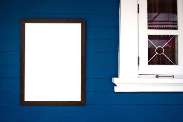 白色内木框架挂在白色窗户附近的蓝色混凝土墙上。图片下载
