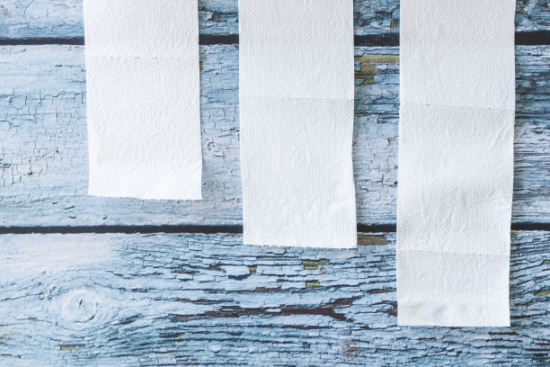 柔软的白色卫生纸卷在蓝色的木制背景上图片下载