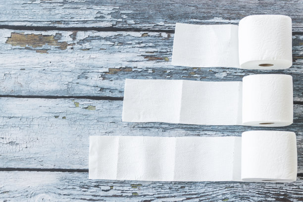 柔软的白色卫生纸卷在蓝色的木制背景上图片下载
