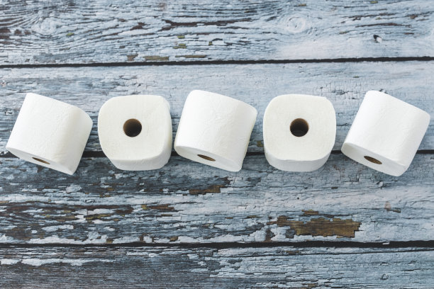 柔软的白色卫生纸卷在蓝色的木制背景上图片下载