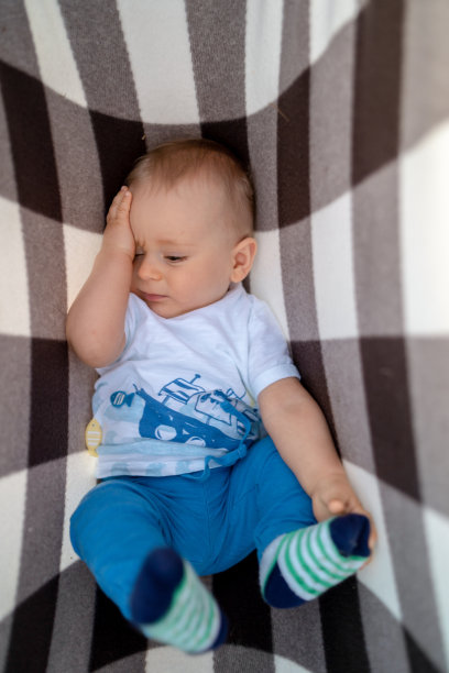 婴儿躺在毯子上让孩子的身体在户外休息。假期和父母。图片下载